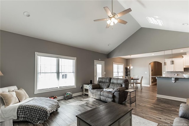 living area with baseboards, arched walkways, ceiling fan, and dark wood-style flooring