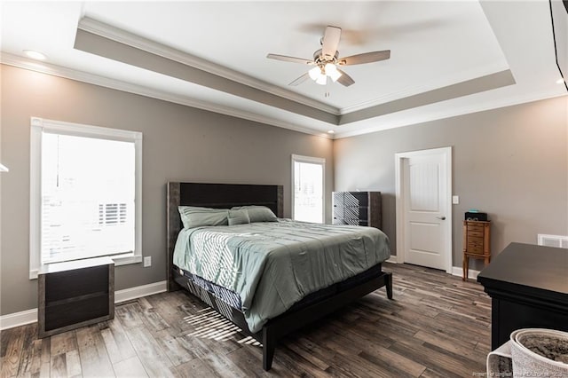 bedroom featuring baseboards, a raised ceiling, and wood finished floors