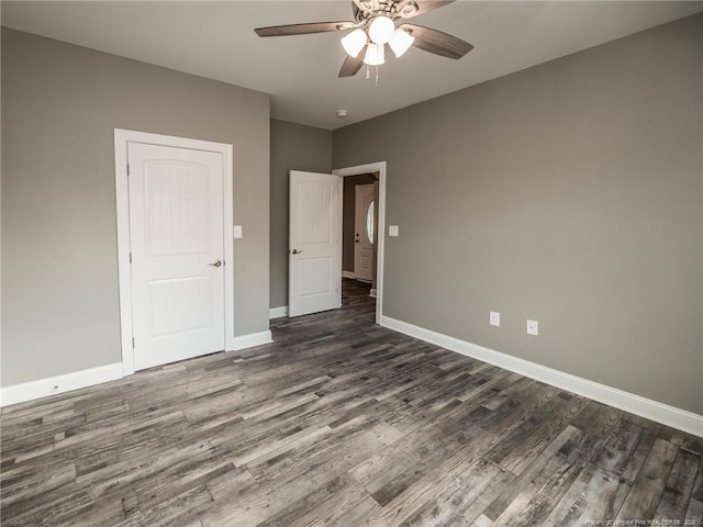 empty room with a ceiling fan, baseboards, and dark wood-style flooring