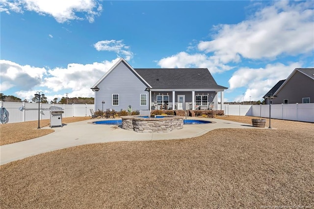 back of house with an outdoor fire pit, a patio area, a fenced backyard, and a fenced in pool