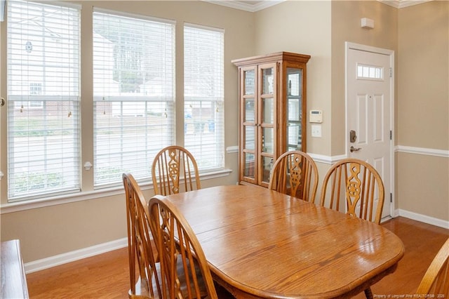 dining space featuring light wood-style floors, ornamental molding, and baseboards