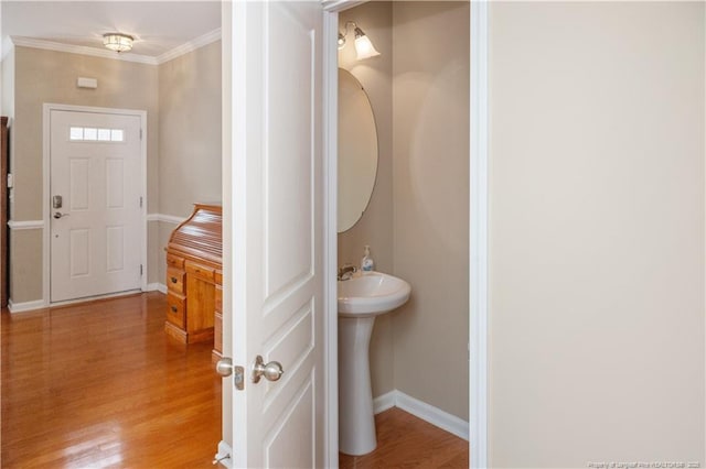 bathroom featuring a sink, crown molding, baseboards, and wood finished floors