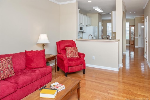 living area with light wood-type flooring, baseboards, and ornamental molding