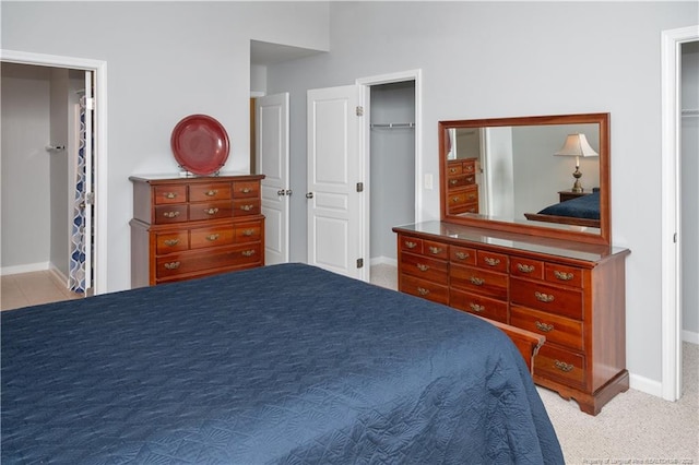 carpeted bedroom featuring a closet, a walk in closet, and baseboards