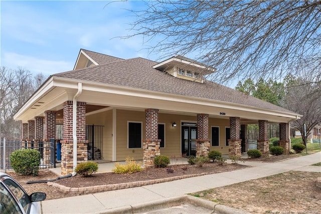 view of front of home with a porch, brick siding, fence, and roof with shingles