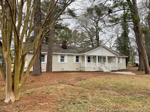 ranch-style home featuring a porch, crawl space, a chimney, and a front lawn