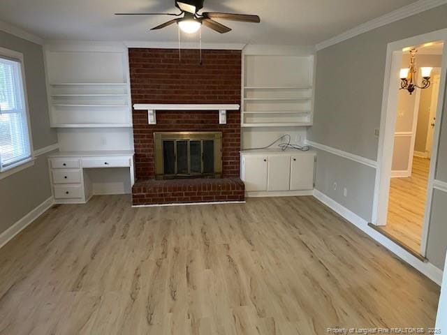 unfurnished living room featuring ceiling fan with notable chandelier, a fireplace, baseboards, light wood-style floors, and ornamental molding