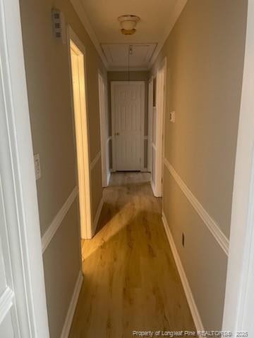 hall with light wood finished floors, attic access, and baseboards