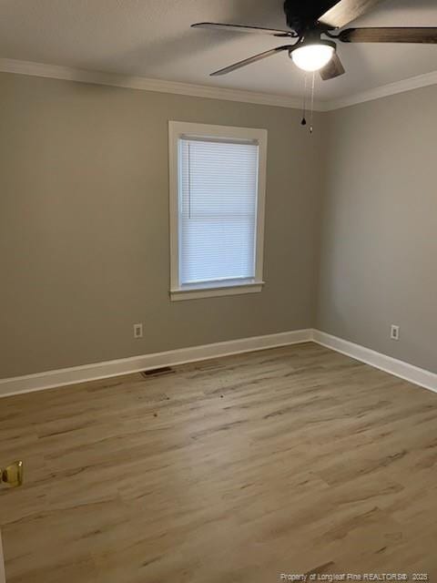 unfurnished room featuring visible vents, ornamental molding, a ceiling fan, wood finished floors, and baseboards