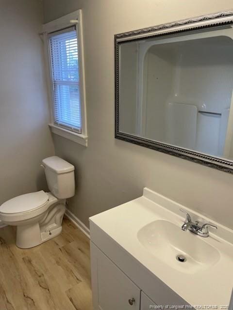 bathroom featuring baseboards, vanity, toilet, and wood finished floors