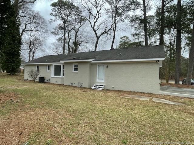 back of property with entry steps, cooling unit, crawl space, a lawn, and stucco siding