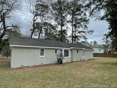 rear view of house with crawl space, fence, and a yard