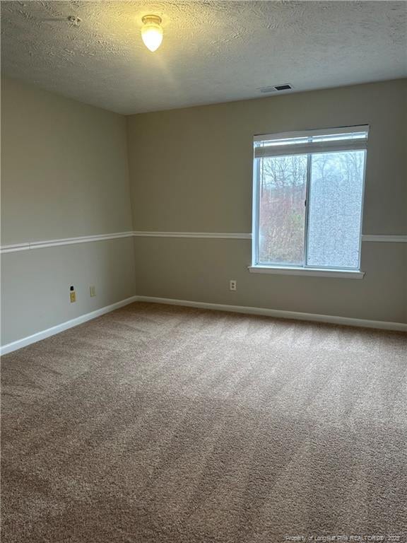 unfurnished room featuring carpet, a textured ceiling, visible vents, and baseboards