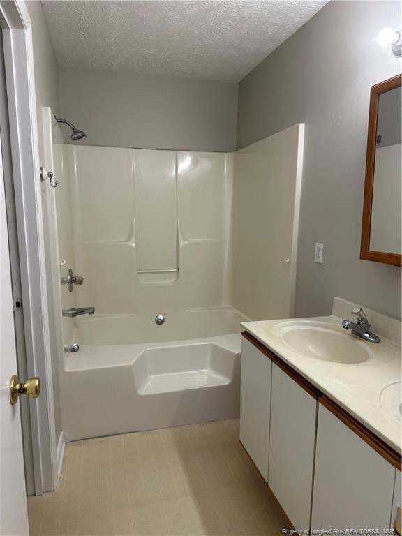 full bath featuring a textured ceiling, double vanity, tub / shower combination, and a sink