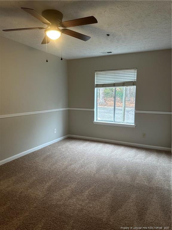 spare room featuring a textured ceiling, carpet flooring, visible vents, and baseboards