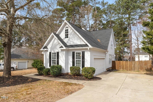 view of front facade with driveway, a shingled roof, and fence