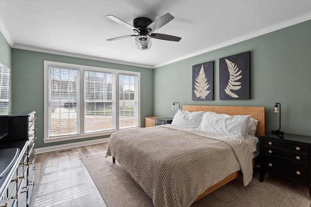 bedroom featuring baseboards, ceiling fan, ornamental molding, and wood finished floors