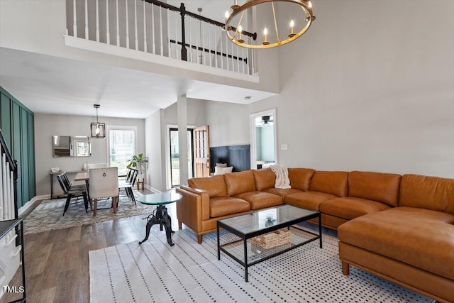 living room featuring a chandelier, baseboards, a towering ceiling, and light wood finished floors