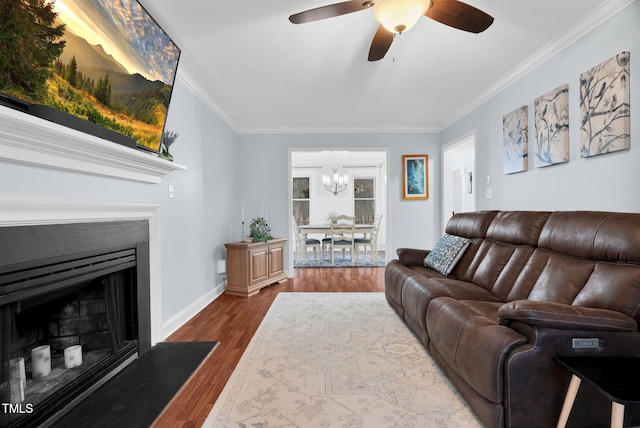 living room featuring baseboards, a fireplace with flush hearth, ornamental molding, dark wood-type flooring, and ceiling fan with notable chandelier