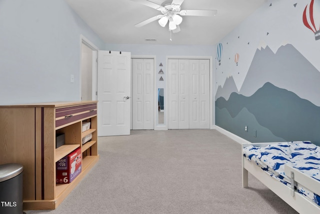 carpeted bedroom featuring baseboards, visible vents, a ceiling fan, and multiple closets