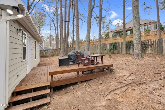 wooden deck featuring a fenced backyard and a grill