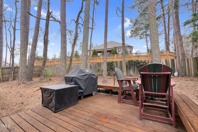 wooden terrace with grilling area and a fenced backyard