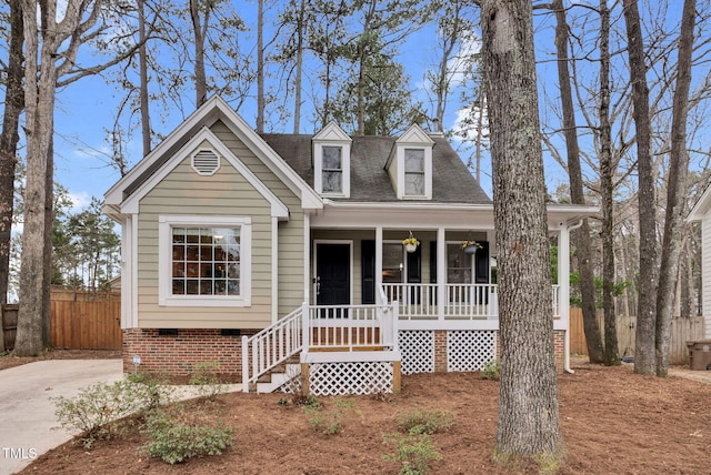 new england style home featuring crawl space, fence, a porch, and roof with shingles