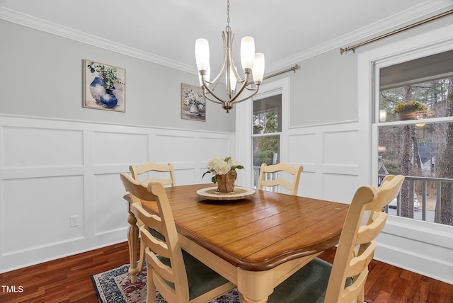 dining area with a chandelier, dark wood finished floors, crown molding, and a decorative wall