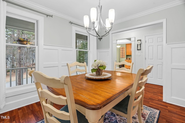 dining space with ornamental molding, dark wood finished floors, a decorative wall, and an inviting chandelier