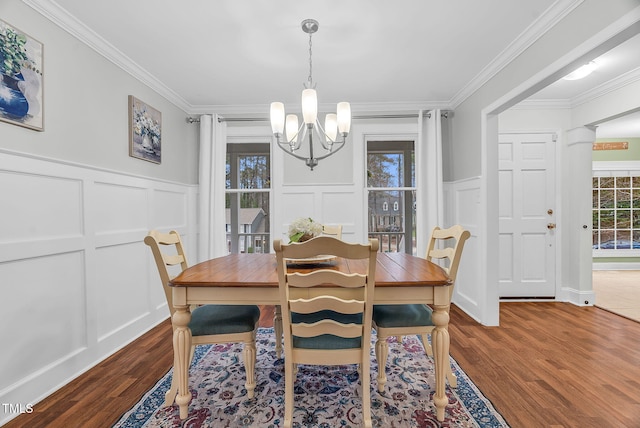 dining area featuring ornamental molding, a notable chandelier, a decorative wall, and wood finished floors