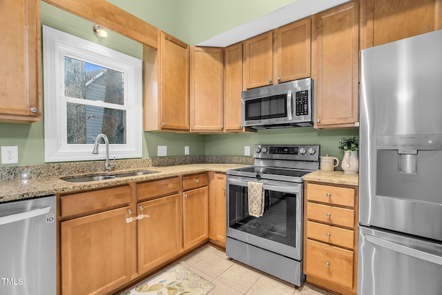 kitchen featuring light tile patterned floors, appliances with stainless steel finishes, a sink, and light stone countertops