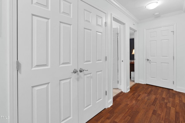 hallway featuring baseboards, dark wood finished floors, and crown molding