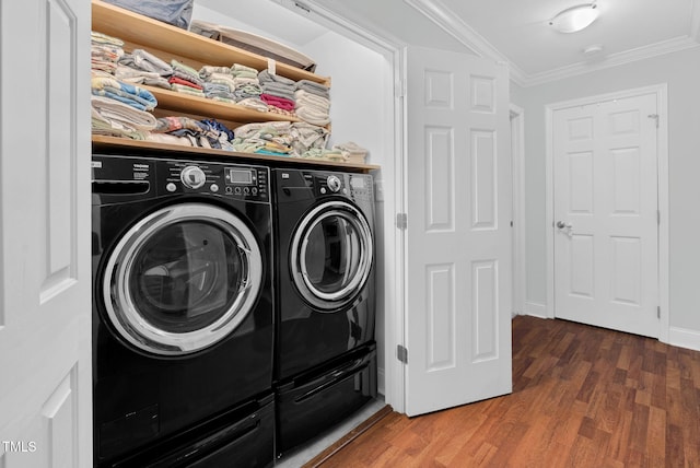 clothes washing area featuring laundry area, wood finished floors, crown molding, and washing machine and clothes dryer