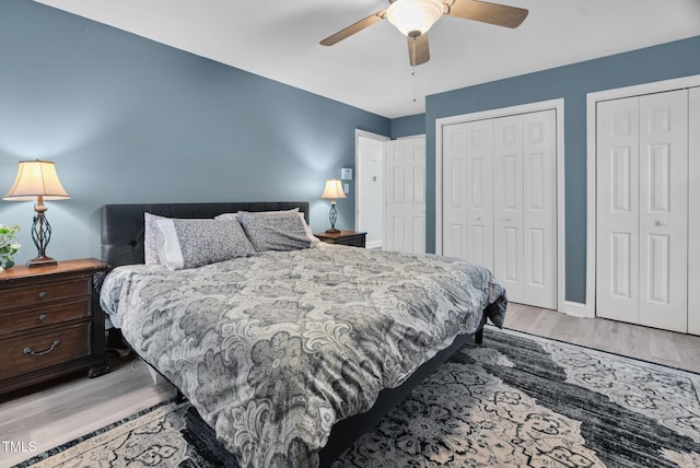 bedroom featuring ceiling fan, light wood finished floors, two closets, and baseboards