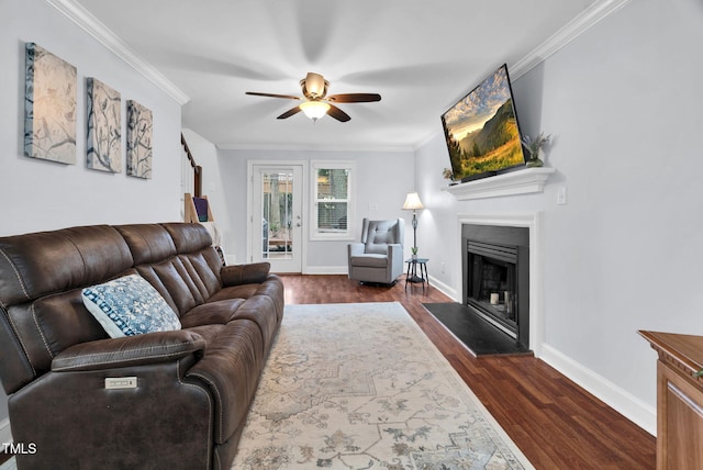 living room featuring ornamental molding, dark wood-style flooring, a fireplace with raised hearth, and baseboards