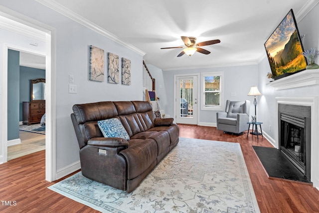 living room featuring a fireplace with flush hearth, ornamental molding, and wood finished floors