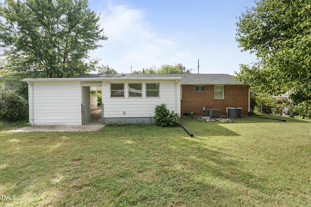 rear view of house featuring central AC, a lawn, and brick siding