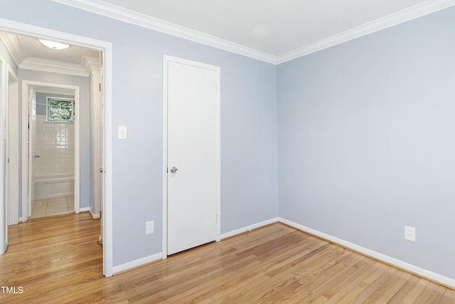 unfurnished room with ornamental molding, light wood-style flooring, and baseboards