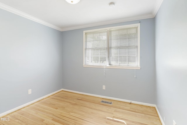 spare room featuring crown molding, wood finished floors, visible vents, and baseboards