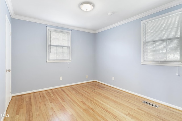 empty room with plenty of natural light, crown molding, visible vents, and wood finished floors