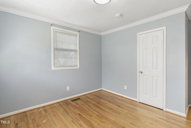 empty room featuring baseboards, light wood-type flooring, visible vents, and crown molding