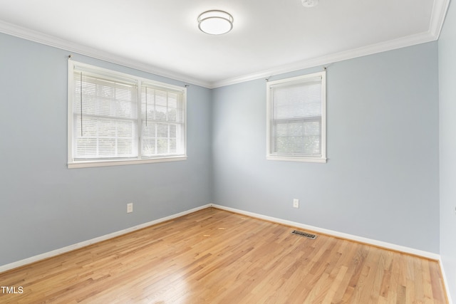 empty room featuring visible vents, crown molding, baseboards, and wood finished floors