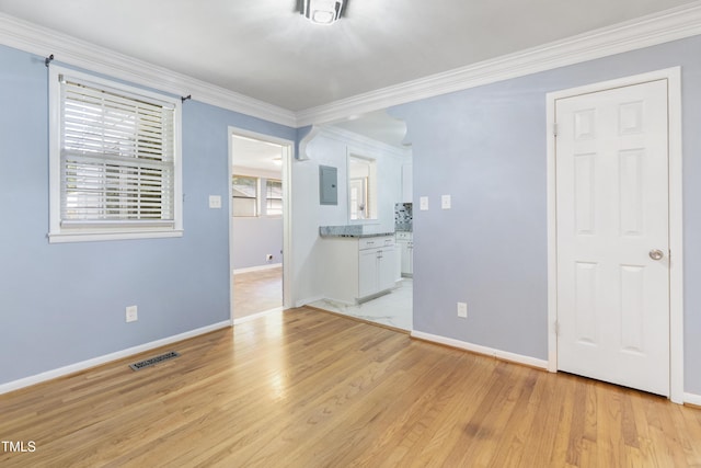 empty room with ornamental molding, baseboards, visible vents, and light wood finished floors