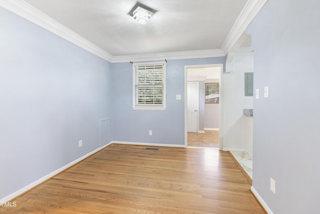 empty room with crown molding, baseboards, visible vents, and light wood-style floors