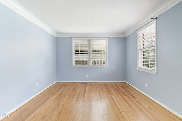 empty room with ornamental molding, wood finished floors, visible vents, and baseboards