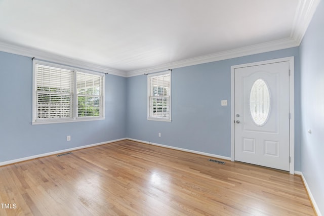 foyer entrance featuring light wood-style floors, baseboards, visible vents, and crown molding