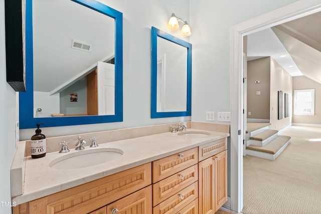 bathroom featuring lofted ceiling, visible vents, a sink, and double vanity