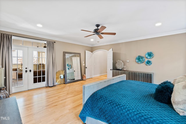 bedroom featuring arched walkways, french doors, crown molding, and wood finished floors