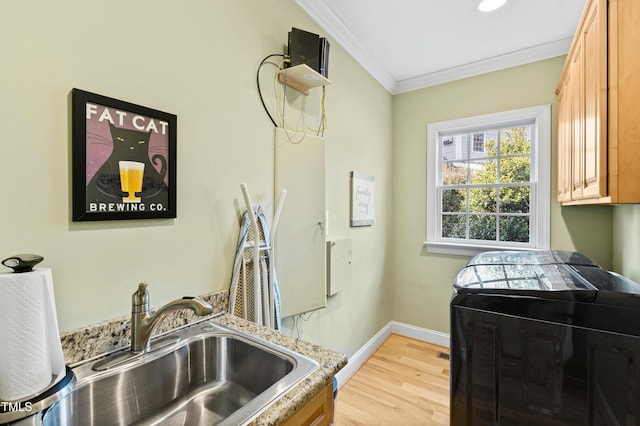 kitchen with washer and clothes dryer, light wood-style flooring, ornamental molding, a sink, and baseboards