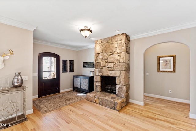 foyer featuring ornamental molding, a fireplace, wood finished floors, and baseboards